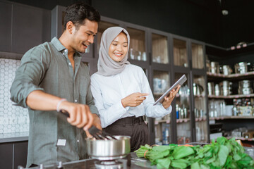 Fototapeta na wymiar muslim couple cooking together in the kitchen while look at video