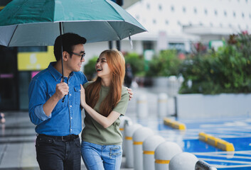 Young Asian couple walking in the rain