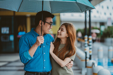 Young Asian couple walking in the rain