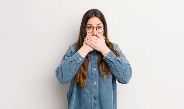 pretty caucasian woman covering mouth with hands with a shocked, surprised expression, keeping a secret or saying oops