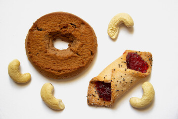 Small heap of the flat crispy puff pastry cookies and heart shaped gingerbreads with sugar icing on a white background 