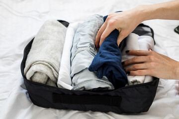 Packing clothes, documents into the suitcase. Travel concept, packing up before departure.