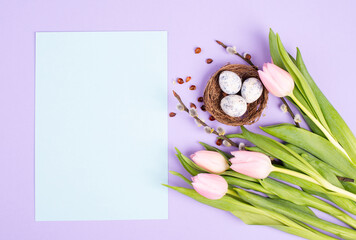 Obraz na płótnie Canvas Nest with small eggs and pink tulips on a purple colored background, easter holiday greeting card, spring season