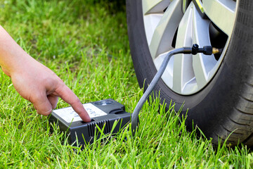 Car wheel pumping with a car compressor. Tire puncture, close-up, background