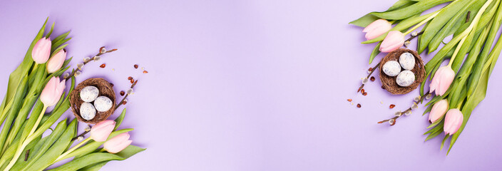 Nest with small eggs and pink tulips on a purple colored background, easter holiday greeting card, spring season