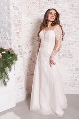 Fototapeta premium The bride in full growth, against the backdrop of a white brick wall.