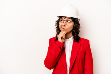 Young architect hispanic woman with helmet isolated on white background looking sideways with doubtful and skeptical expression.