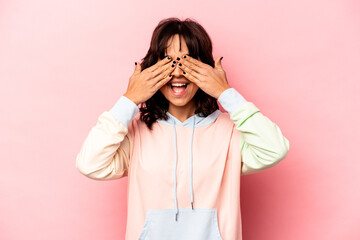 Young hispanic woman isolated on pink background covers eyes with hands, smiles broadly waiting for a surprise.