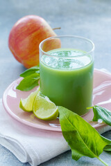 Fototapeta premium Green smoothie with spinach leaves, lime juice and apple in a glass, close-up