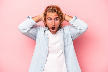 Young caucasian man isolated on pink background screaming, very excited, passionate, satisfied with something.