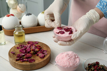 Woman in gloves making bath bomb at white table indoors, closeup
