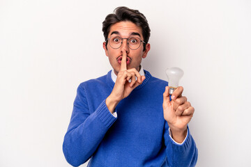 Young caucasian man holding a lightbulb isolated on white background keeping a secret or asking for silence.
