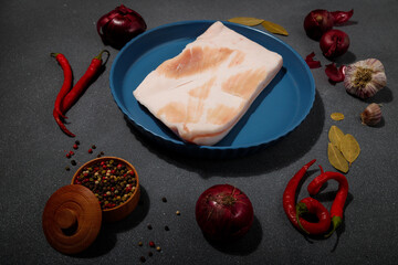 Piece of raw pork lard and ingredients for marinade: onions, garlic, red hot pepper, salt, bay leaf...