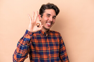 Young caucasian man isolated on beige background cheerful and confident showing ok gesture.