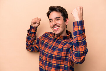 Fototapeta premium Young caucasian man isolated on beige background cheering carefree and excited. Victory concept.