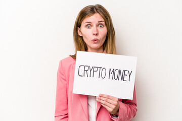 Young English business woman holding a crypto money placard isolated on white background shrugs...