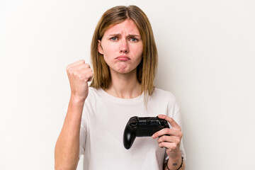 Young English woman playing with a video game controller isolated white background showing fist to camera, aggressive facial expression.