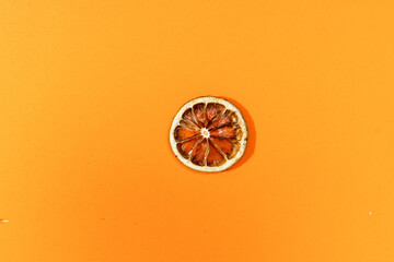 Dissected orange slice on a orange surface.
