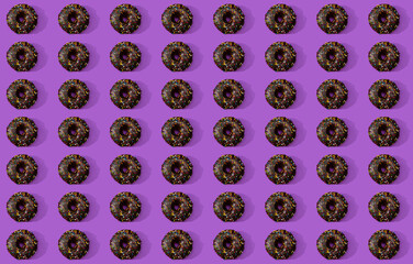A mosaic-like arrangement of a fresh donuts on a purple surface.
