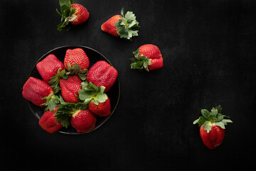 Bowl with delicious, red and juicy strawberries. Top view of a box with ripe strawberries on a dark background