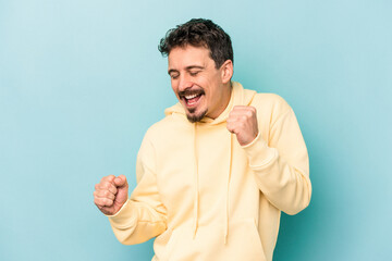 Young caucasian man isolated on blue background dancing and having fun.
