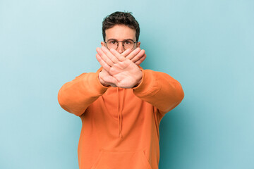 Young caucasian man isolated on blue background doing a denial gesture