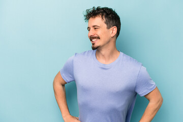 Obraz premium Young caucasian man isolated on blue background confident keeping hands on hips.