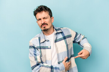 Young caucasian man isolated on blue background having a liver pain, stomach ache.