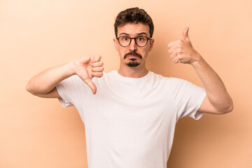 Fototapeta premium Young caucasian man isolated on beige background showing thumbs up and thumbs down, difficult choose concept