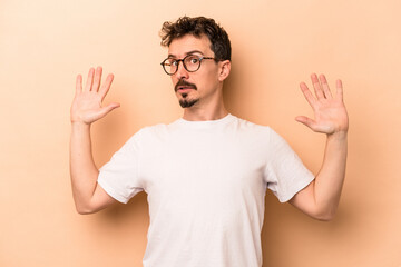 Young caucasian man isolated on beige background being shocked due to an imminent danger
