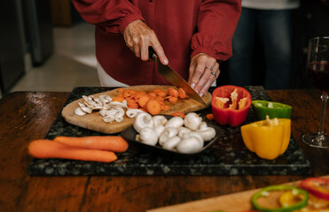 Obraz na płótnie Canvas caucasian senior female cooking in kitchen chopping vegetables
