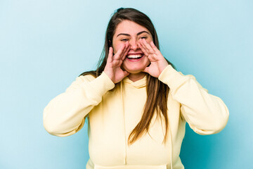 Young caucasian overweight woman isolated on blue background saying a gossip, pointing to side reporting something.