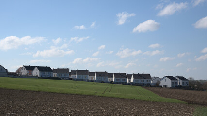Fototapeta na wymiar A row of newly built semi- detached houses on the horizon with blue cloudy sky.
