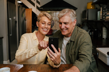 Caucasian senior couple texting on cellular device 