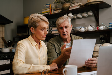 Fototapeta na wymiar Caucasian senior couple working from home looking at bills and payments