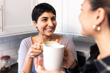 Happy smiling women having a cup of tea or coffee at home