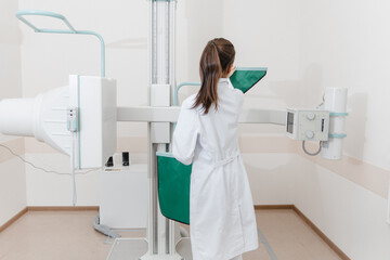 Hospital Radiology Room. Xray machine for fluorography. Doctor radiologist in gown adjusting the...