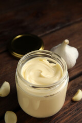 Jar of delicious mayonnaise and fresh garlic on wooden table
