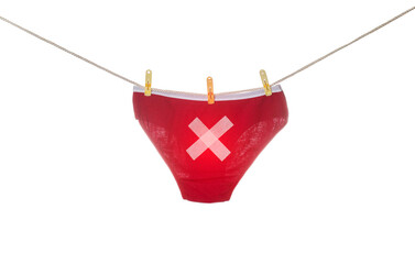 Women's red panties with a cross hanging on a clothesline, white background, isolate. Concept of...