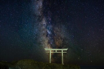 Starry landscape view with shrine gate and the Milky Way on the sea horizon in the night in Japan
