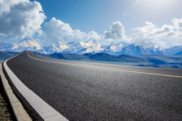 Fototapeten Empty asphalt road and snow mountain natural landscape under blue sky © ABCDstock