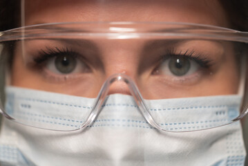 Young woman doctor or nurse working. Girl in medical mask, glasses and shield.