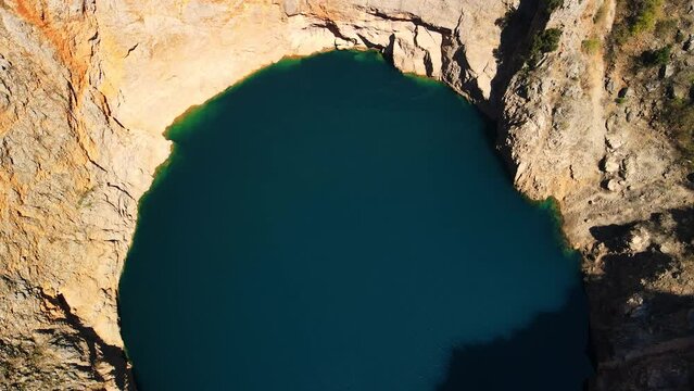 Flying over the Red Lake containing a karst lake close to Imotski, Croatia. The largest collapse doline in Europe with high cliffs and great depths. 4k UHD