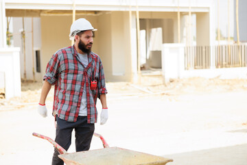 Construction worker wearing protect gloves and hardhat helmet mix cement to building in construction site.