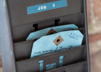 Old clocking in to work project card. Blue work ticket for punching ion in retro wooden holder.