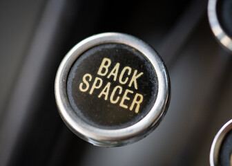 Retro vintage back spacer typewriter circular round key closeup with gold coloured back space key...