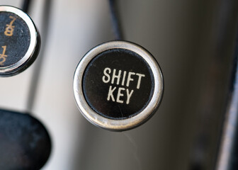 Retro vintage typewriter circular round key closeup with gold coloured shift key on black background.