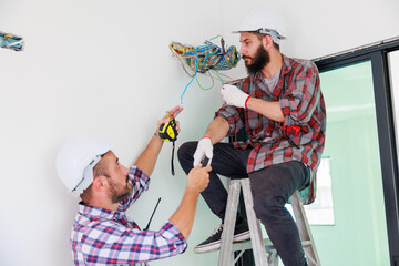 Two electricians and builder helping to install the electrical system in the house under construction. Maintenance service Repair and handyman concept