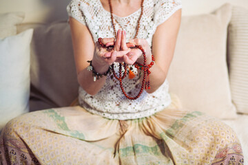 Woman at meditate place in lotus position using Mudra,  hand close up, strands of  beads used for...