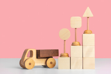 Wooden toy car truck and toy road signs stand on wooden cubes arranged in the form of a pyramid staircase. Mockup for delivery business, logistics. Copyspace